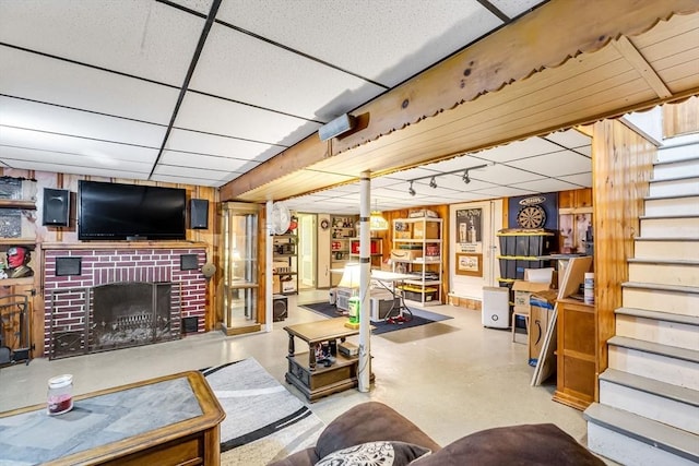 59 Kulig St, Springfield, MA 01104 - living room featuring a paneled ceiling, stairway, concrete flooring, a fireplace, and wooden walls
