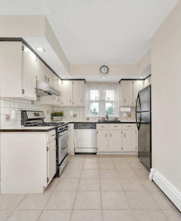 131 Beacon St Unit 4, Chelsea, MA 02150 - kitchen with stainless steel appliances, under cabinet range hood, baseboard heating, a sink, and backsplash
