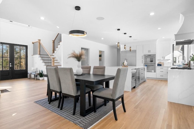 dining space with sink, light hardwood / wood-style floors, and french doors