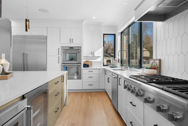 kitchen featuring white cabinetry, appliances with stainless steel finishes, beverage cooler, and wall chimney exhaust hood