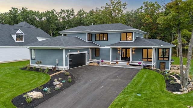 view of front of home featuring a porch, a garage, and a lawn