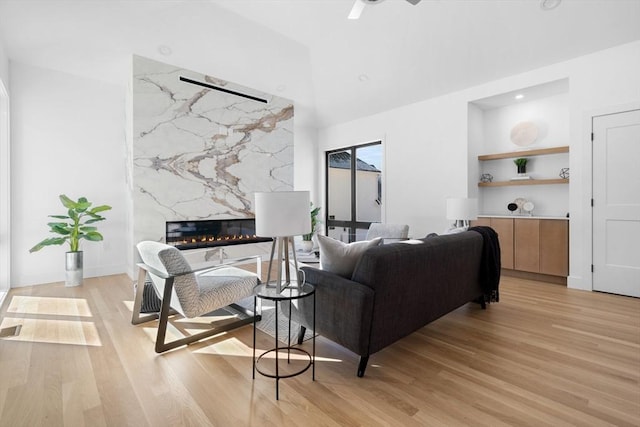 living room featuring ceiling fan, a fireplace, and light hardwood / wood-style floors