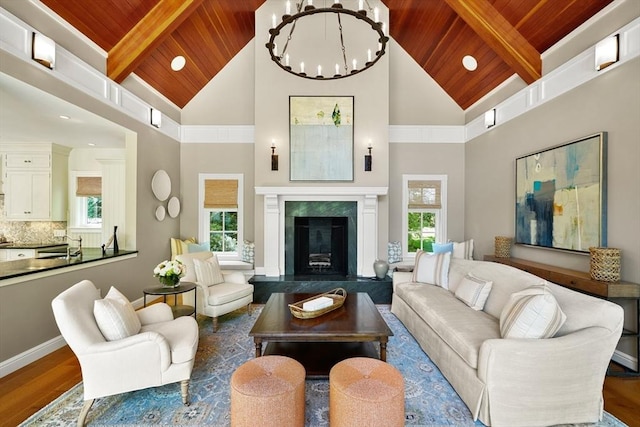 living area featuring a high end fireplace, beamed ceiling, wood ceiling, and wood finished floors