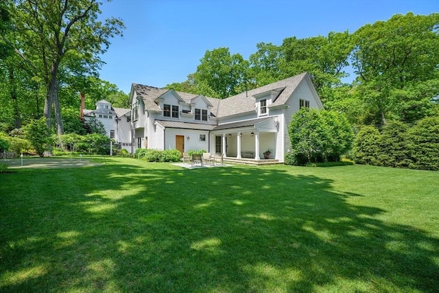 rear view of property featuring a yard, a patio, metal roof, and a standing seam roof