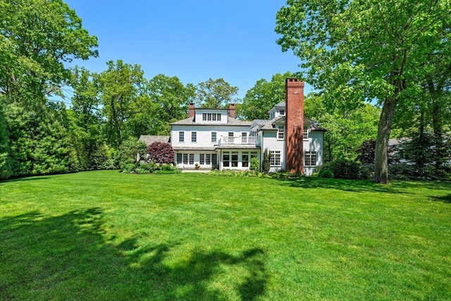 back of house featuring a lawn and a chimney