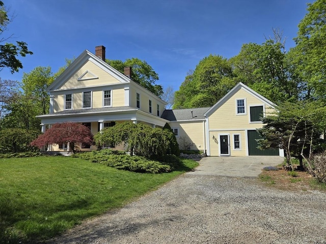 view of front of house featuring driveway, a chimney, and a front yard