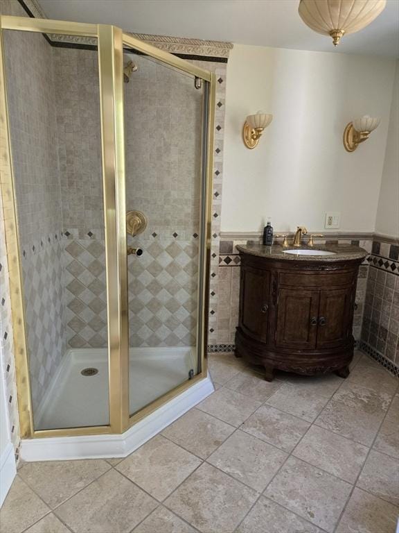 full bath featuring wainscoting, tile patterned flooring, vanity, tile walls, and a stall shower