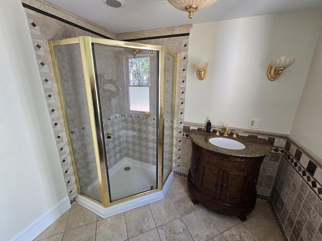 bathroom with tile patterned flooring, vanity, tile walls, and a shower stall