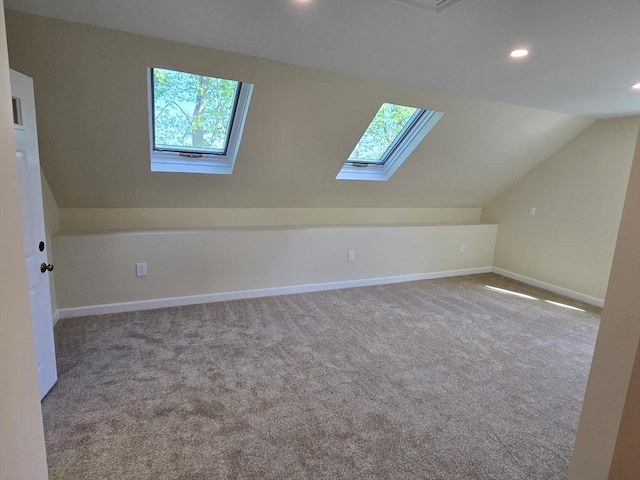 additional living space featuring vaulted ceiling with skylight, plenty of natural light, carpet flooring, and recessed lighting