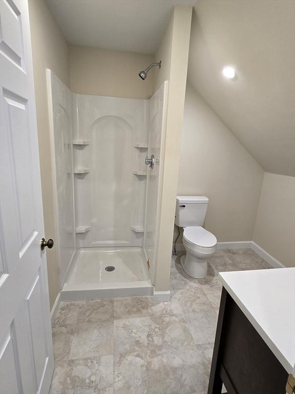 bathroom featuring vanity, baseboards, walk in shower, and toilet