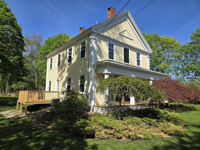 exterior space with a deck, a chimney, and central AC unit