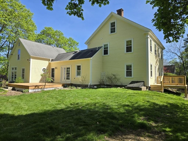 back of house with a lawn, a wooden deck, and a chimney