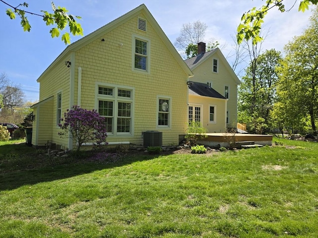 rear view of property with a lawn, cooling unit, a chimney, and a wooden deck