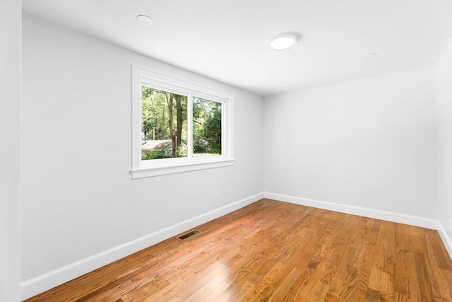 empty room with light wood-style floors, baseboards, and visible vents