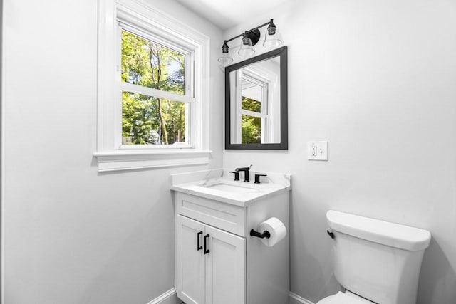 half bath with vanity, baseboards, and toilet