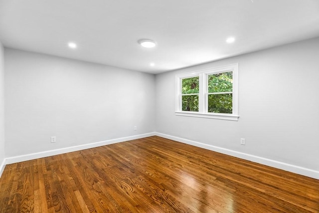 spare room with baseboards, recessed lighting, and wood finished floors