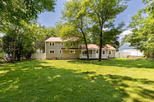 rear view of house featuring a wooden deck, a fenced backyard, and a lawn
