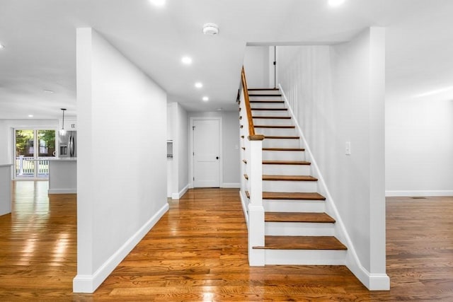 staircase featuring recessed lighting, baseboards, and wood finished floors