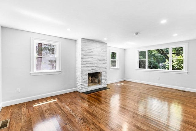 unfurnished living room featuring visible vents, baseboards, wood finished floors, and a fireplace