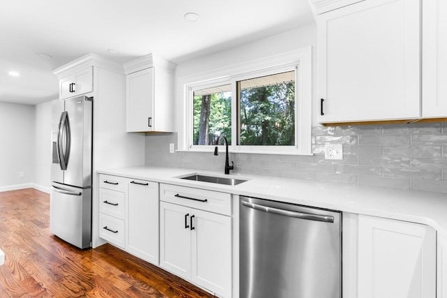 kitchen with a sink, light countertops, appliances with stainless steel finishes, and dark wood-style floors