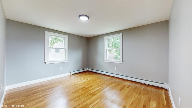 unfurnished room featuring a healthy amount of sunlight, a baseboard radiator, and wood-type flooring