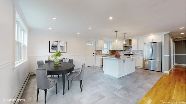 kitchen with a center island, decorative light fixtures, stainless steel appliances, white cabinets, and a baseboard radiator