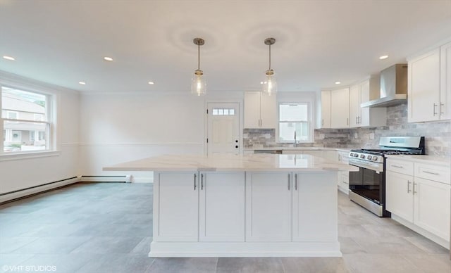 kitchen with a kitchen island, white cabinets, gas range, and wall chimney range hood