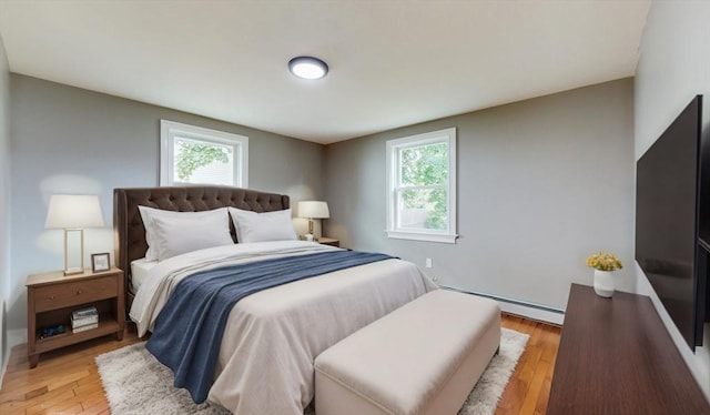 bedroom with light hardwood / wood-style floors and a baseboard radiator