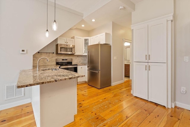 kitchen with tasteful backsplash, visible vents, a peninsula, stainless steel appliances, and a sink