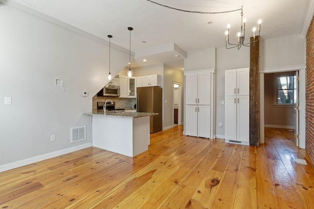 kitchen featuring visible vents, appliances with stainless steel finishes, a peninsula, white cabinetry, and a sink