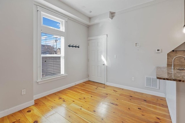 unfurnished room featuring a sink, visible vents, baseboards, and light wood-style flooring