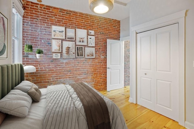 bedroom with a closet, brick wall, and hardwood / wood-style floors