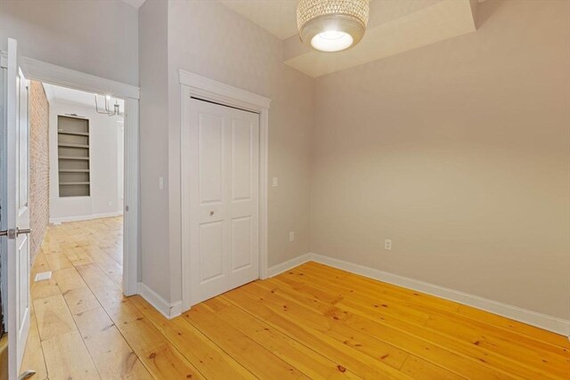 unfurnished bedroom with a closet, baseboards, and light wood finished floors