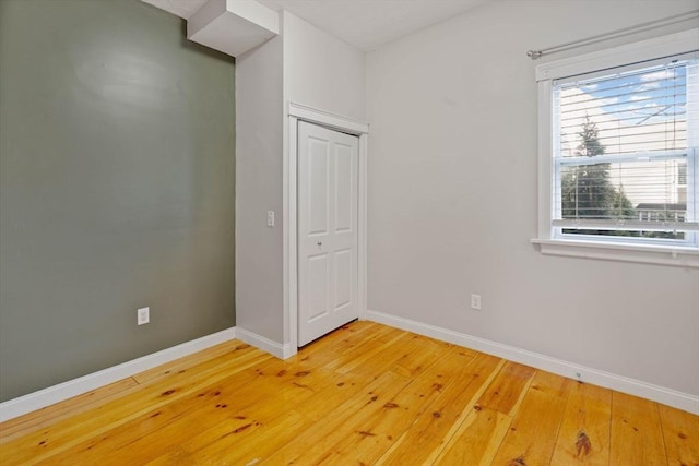 unfurnished bedroom with a closet, light wood-type flooring, and baseboards