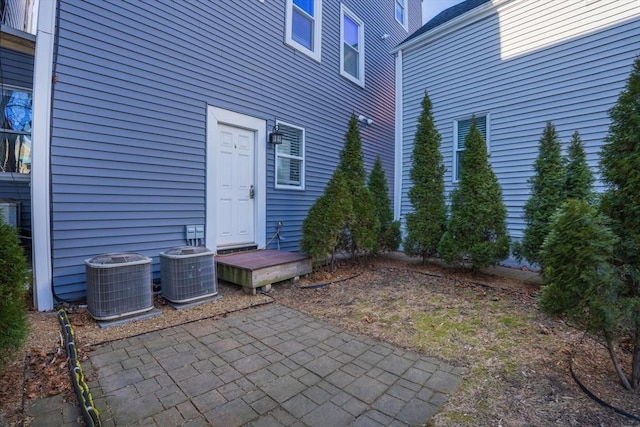 view of exterior entry with a patio area and central AC unit