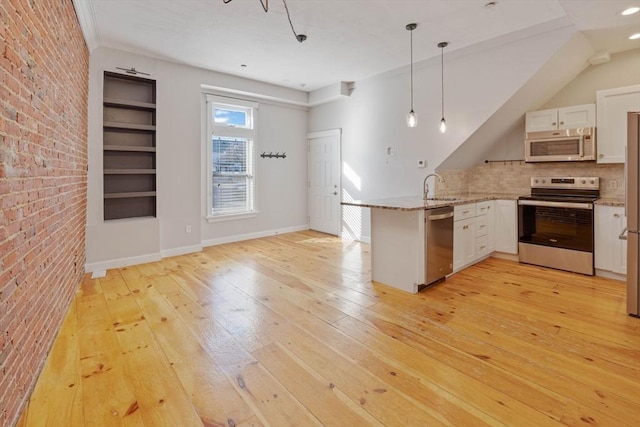 kitchen with a sink, appliances with stainless steel finishes, a peninsula, and light wood finished floors