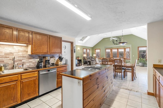 kitchen featuring brown cabinetry, stainless steel appliances, a sink, and light tile patterned flooring