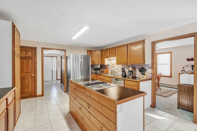 kitchen featuring a baseboard radiator, a sink, appliances with stainless steel finishes, backsplash, and a center island