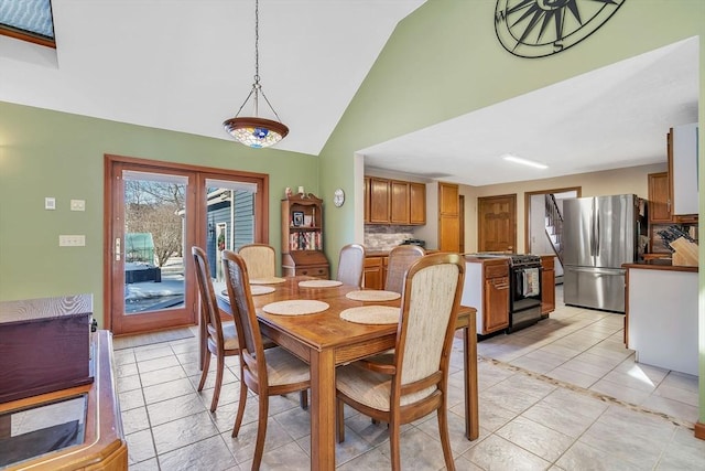 dining space featuring light tile patterned floors and high vaulted ceiling