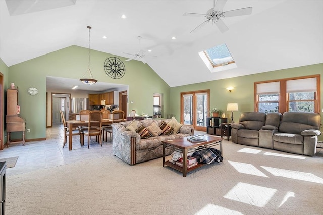 living room featuring a skylight, light colored carpet, light tile patterned flooring, ceiling fan, and high vaulted ceiling