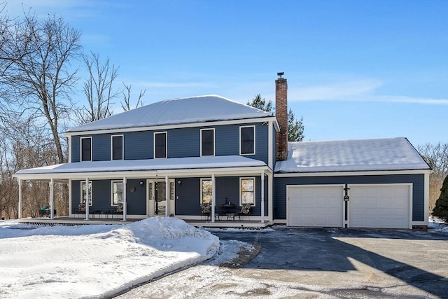 view of front facade with a garage, covered porch, a chimney, and aphalt driveway