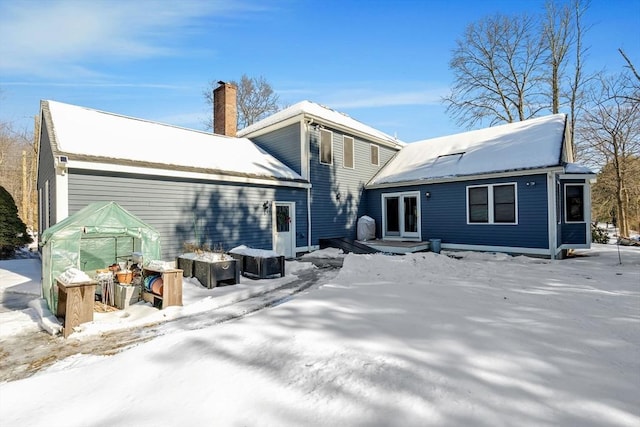 snow covered house featuring a chimney