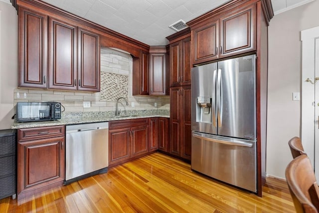 24-26 Lincoln St, North Andover, MA 01845 - kitchen with appliances with stainless steel finishes, light wood-style flooring, tasteful backsplash, light stone countertops, and crown molding
