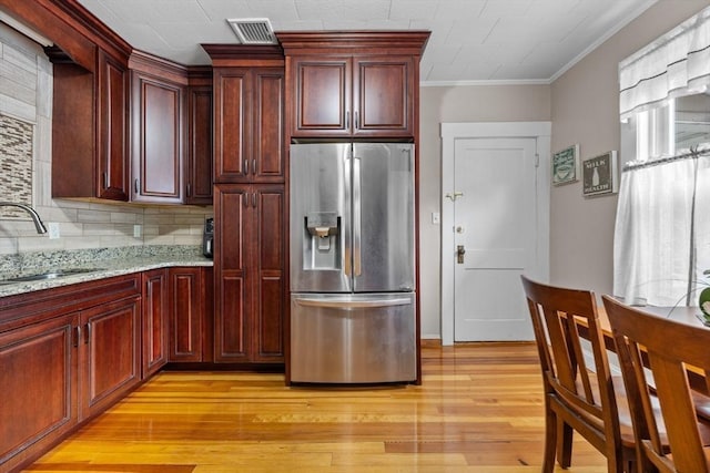 24-26 Lincoln St, North Andover, MA 01845 - kitchen with stainless steel fridge, reddish brown cabinets, backsplash, light wood-style floors, and light stone countertops