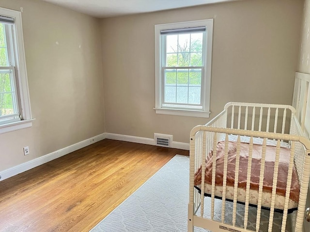 bedroom featuring multiple windows, wood finished floors, and baseboards