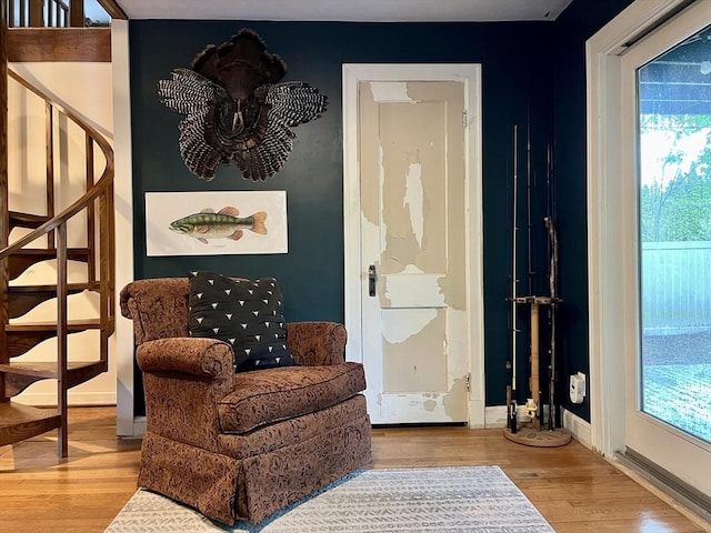 living area with wood finished floors, stairway, and baseboards