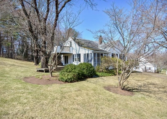 view of side of home with a chimney, a yard, and a deck