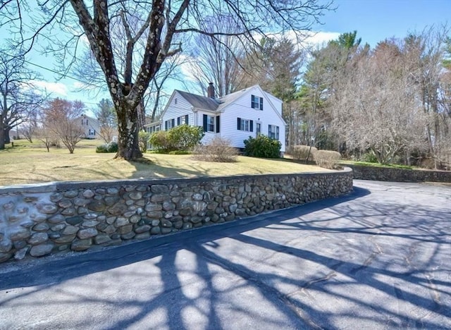view of side of home featuring a chimney and a yard