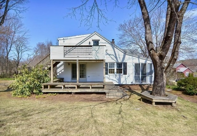 view of front facade featuring a wooden deck, a front lawn, stairway, and a sunroom