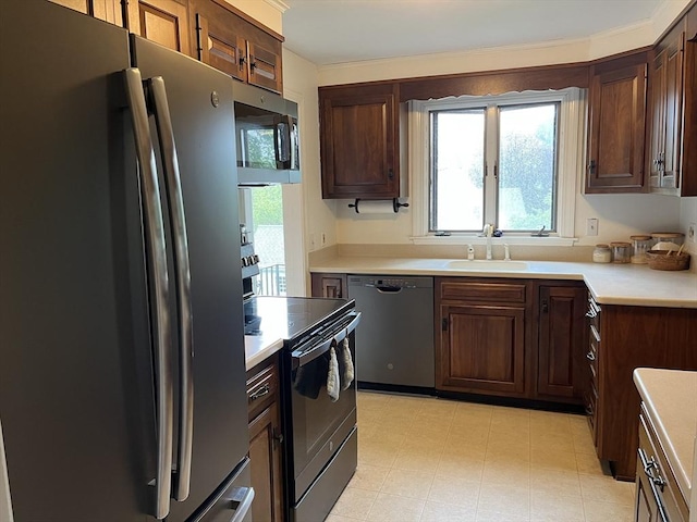 kitchen featuring stainless steel appliances, a sink, and light countertops